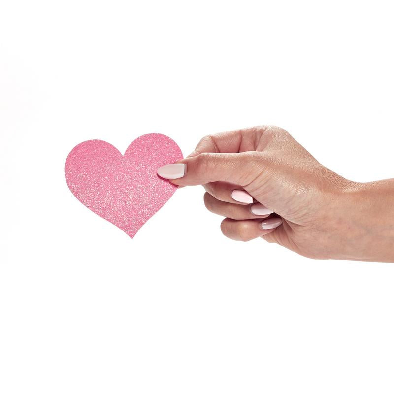 Hand holding a pink heart-shaped object on a white background