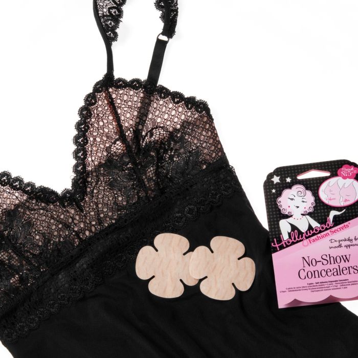 Two flower-shaped nipple covers rest on a black lace chemise next to their Hollywood Fashion Secrets packaging.
