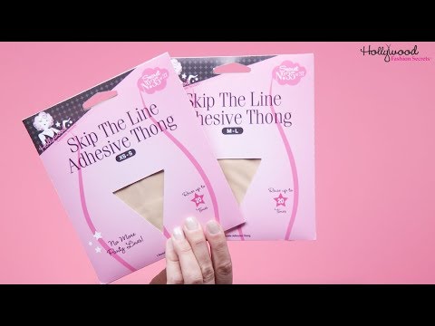 A hand displays two packages of Hollywood Fashion Secrets Skip The Line Adhesive Thong, a reusable no-show underwear solution, against a pink background.