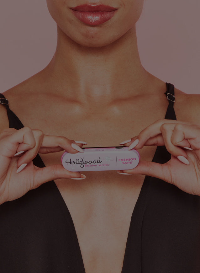 Female holding fashion tape against a pink background