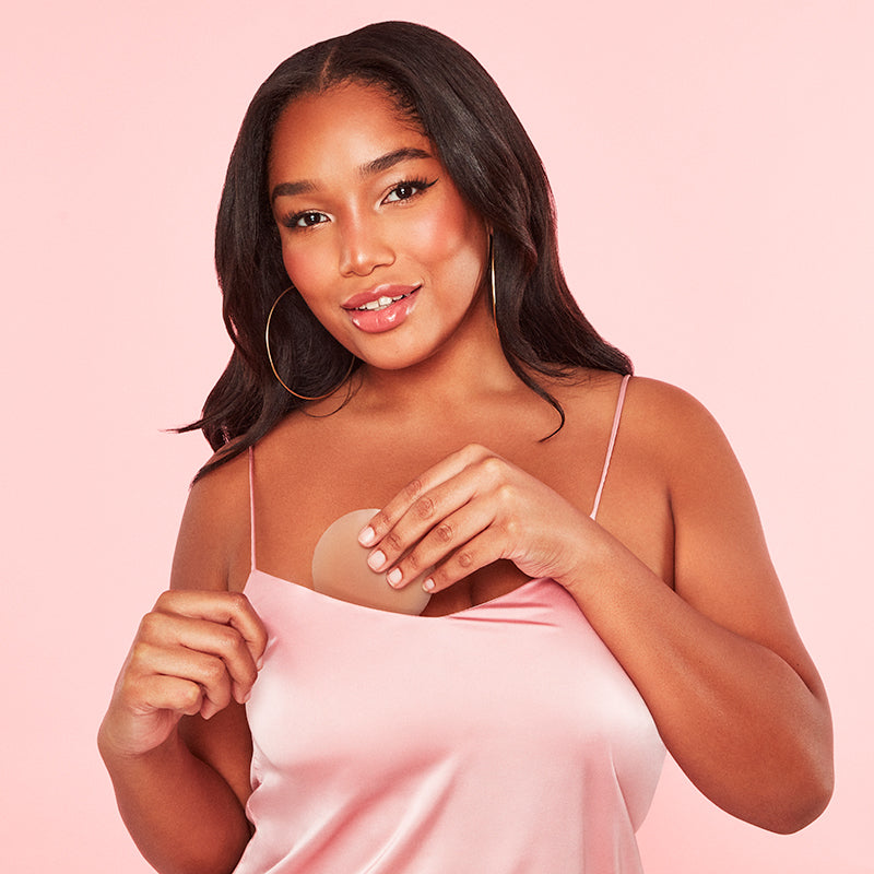 Woman applying a adhesive patch on her chest against a pink background