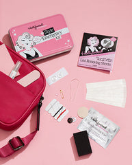 Flat lay of Hollywood Fashion Secrets Style Emergency Kit with beauty and fashion essentials in a pink travel case.