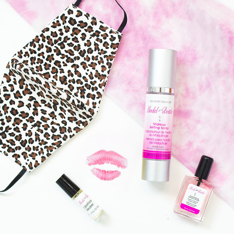 Makeup products including a leopard print pouch, bottles, and a spray on a pink and white background.
