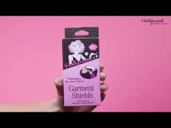 Hand holding Hollywood Fashion Secrets Garment Shields packaging against a pink background.